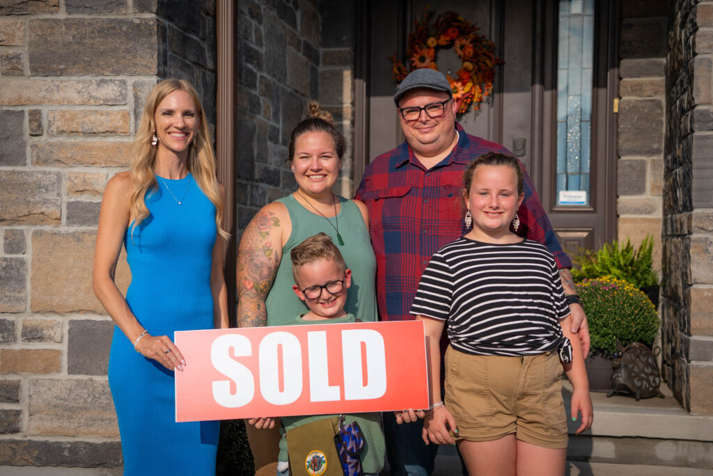 Kayla Nieman REALTOR with happy home buyers holding SOLD sign in Ottawa Valley